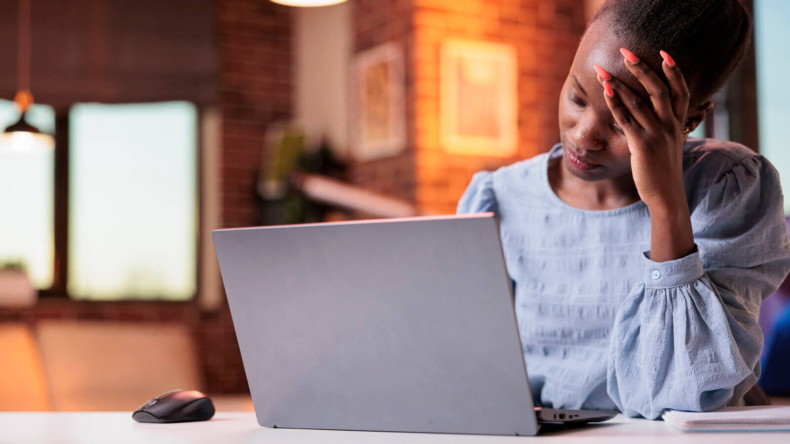 Tired woman on a laptop with her hand on her forehead.