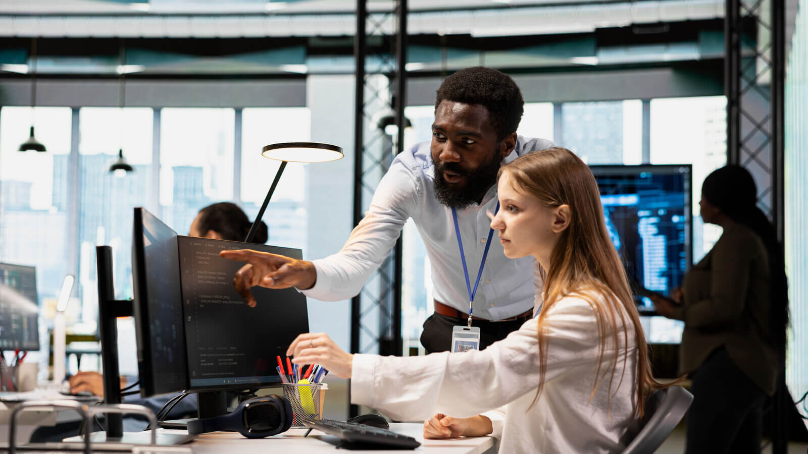 student intern is mentored next to a computer screen