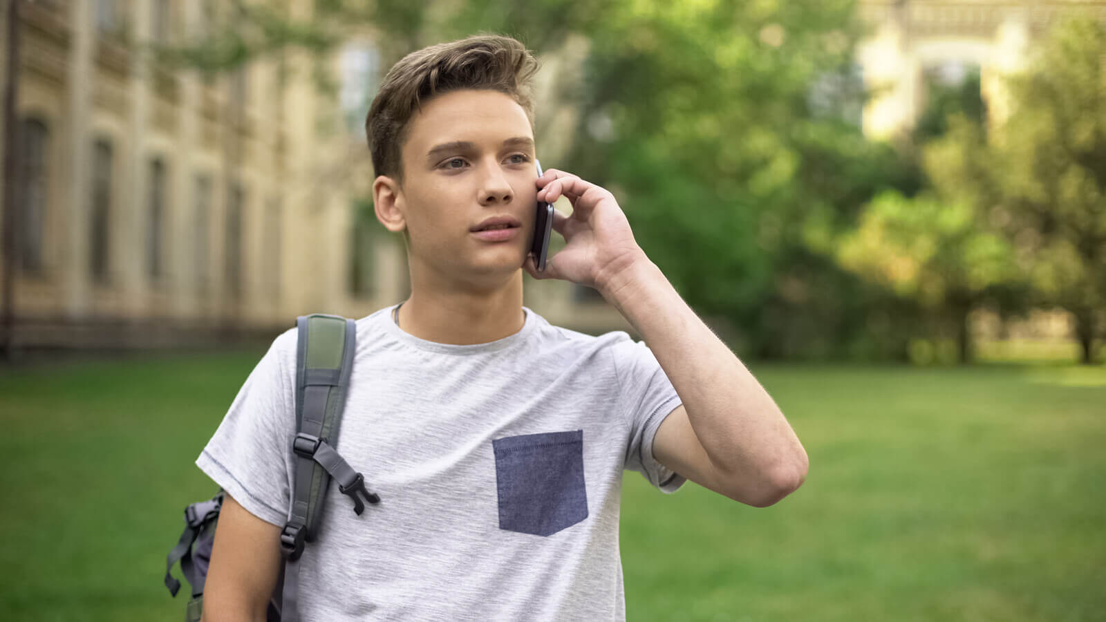 college student on the phone in a green lawn