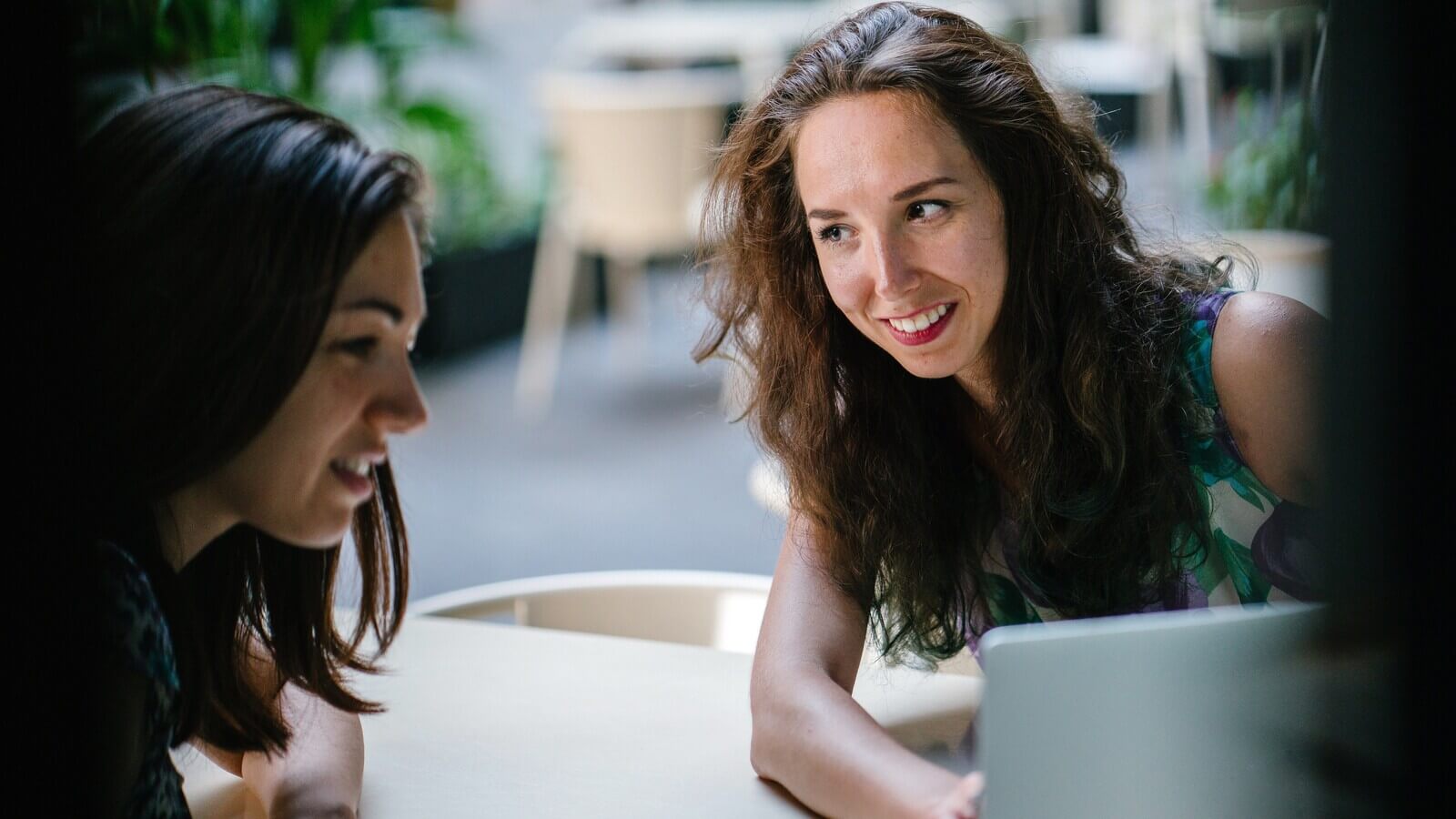 A woman and student smiling and looking at a laptop together.