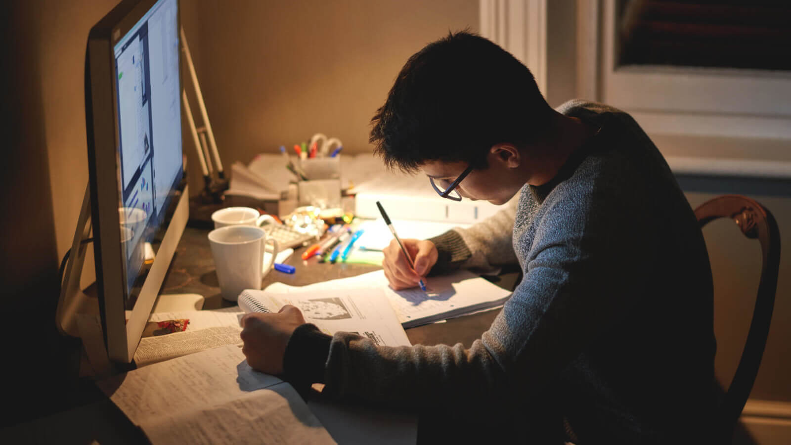 a boy does homework at his desk at home