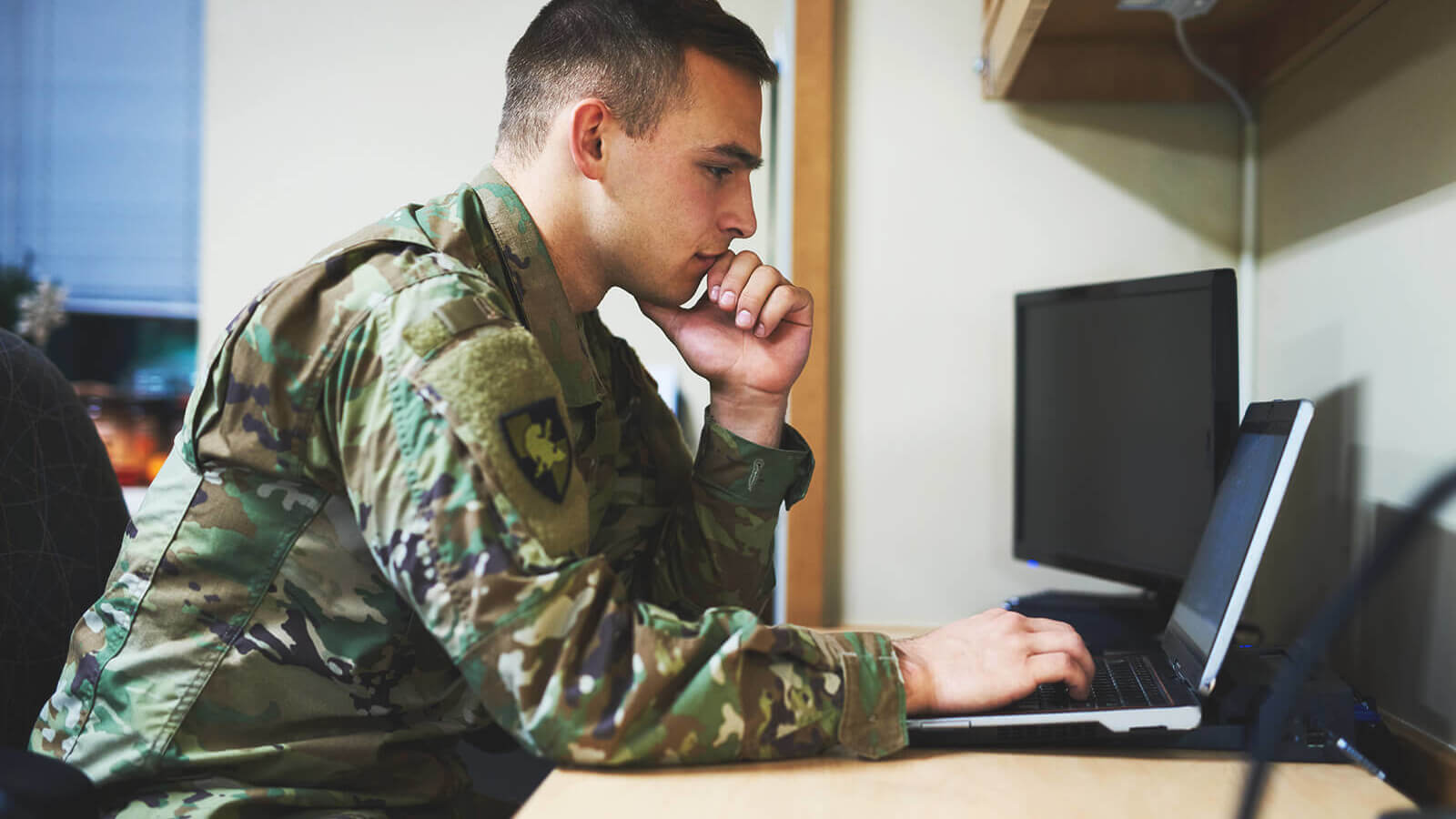a man in a military uniform looks at his laptop