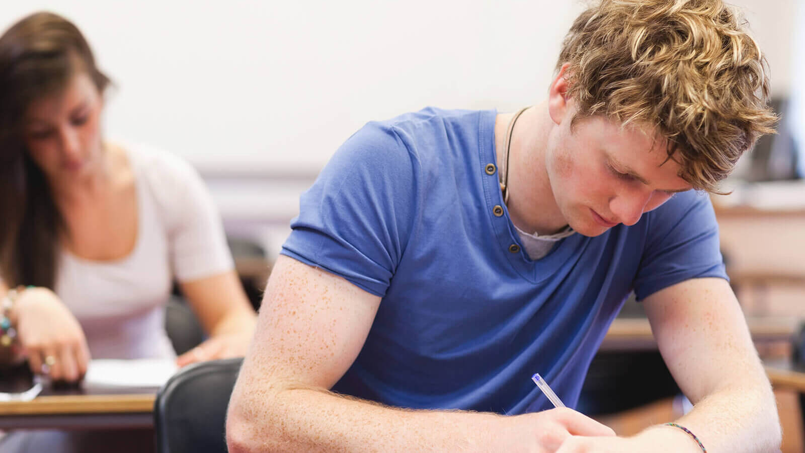 A male student focusing on coursework in class.