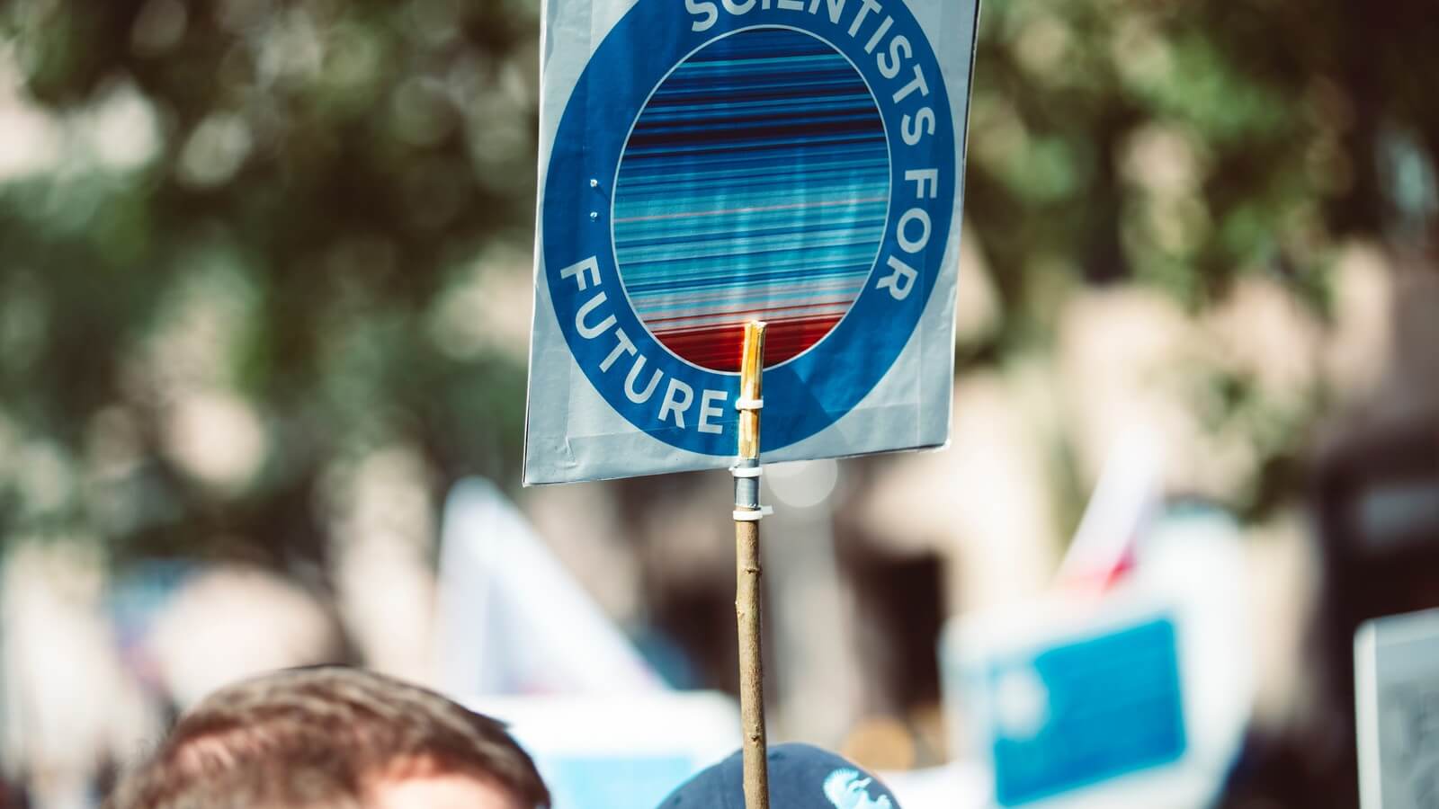 IMAGE: People at a rally with a sign held up overhead saying "Scientist for Future." 