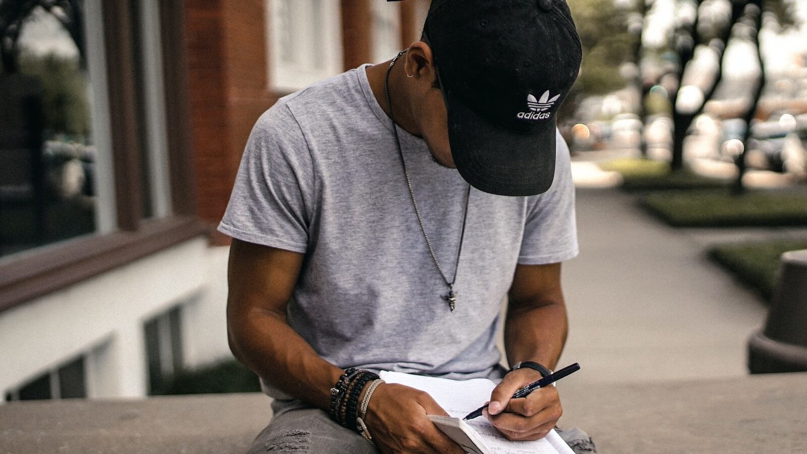 a male student practices for the ACT in a notebook outside on a bench