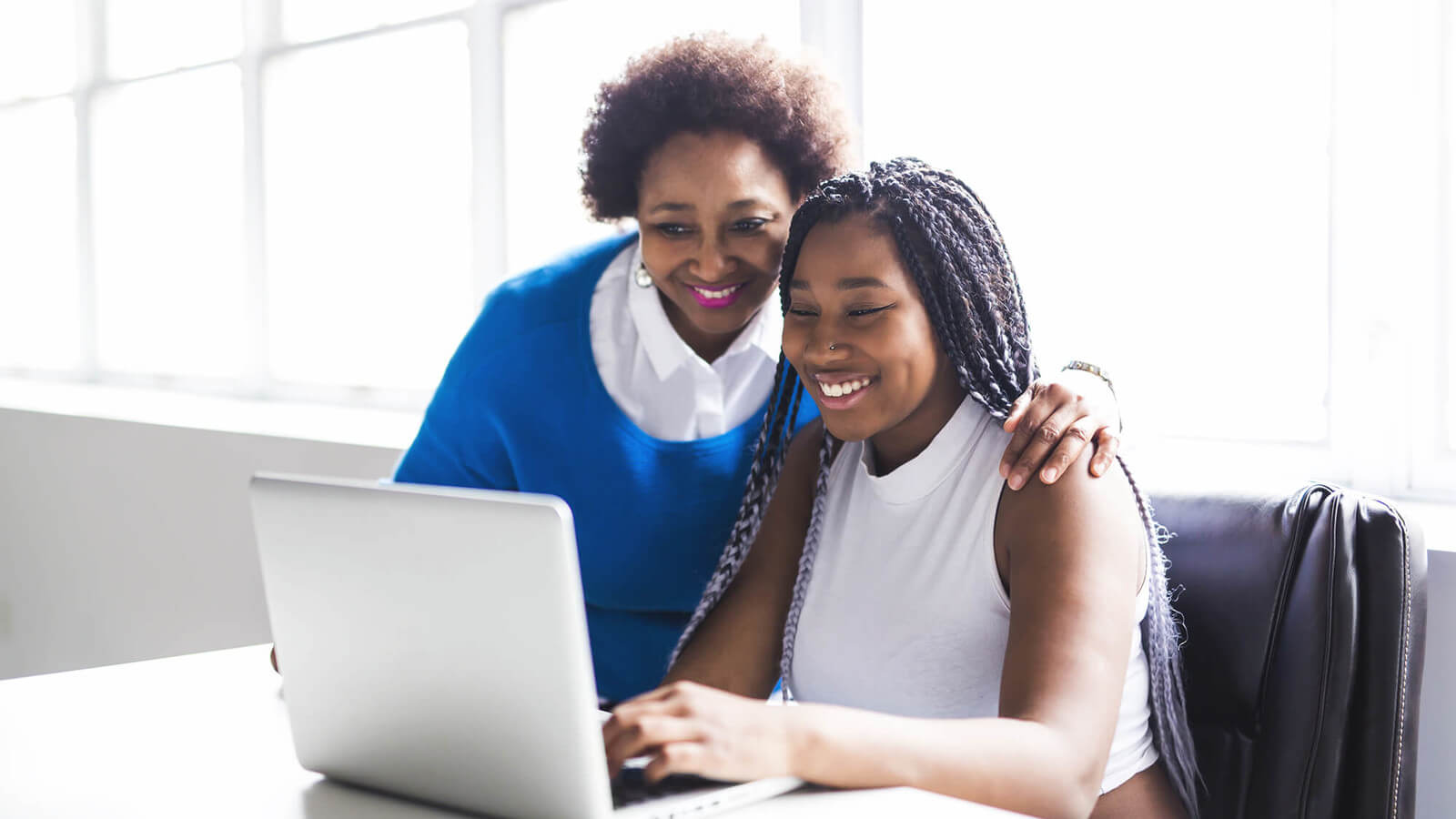 a mother and daughter look at a laptop and financial aid application