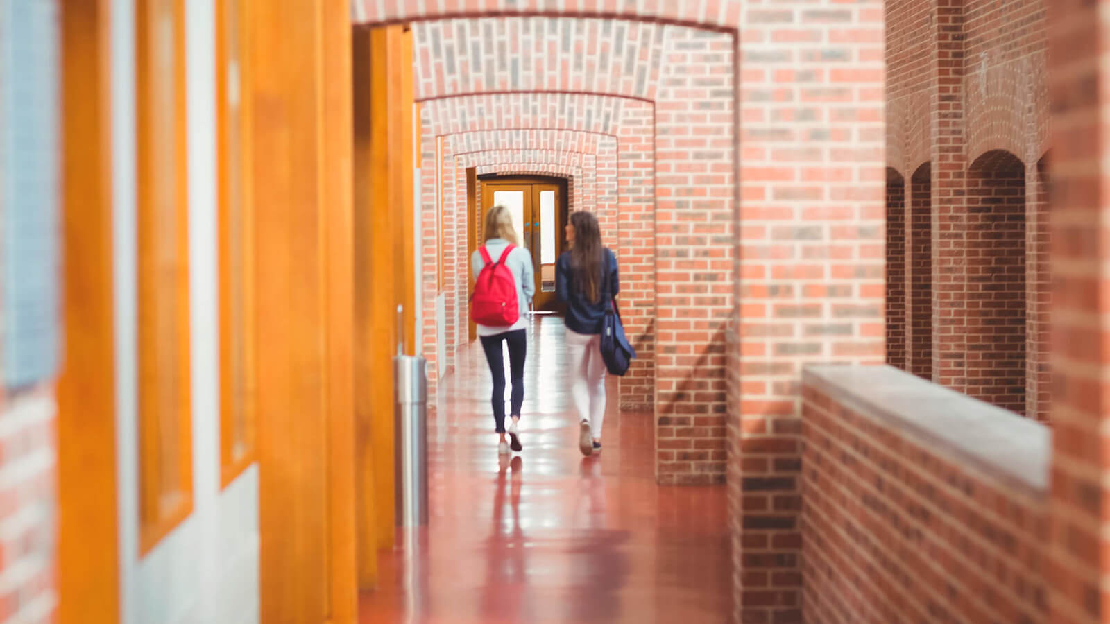 two female students walk down a long hallway ay college