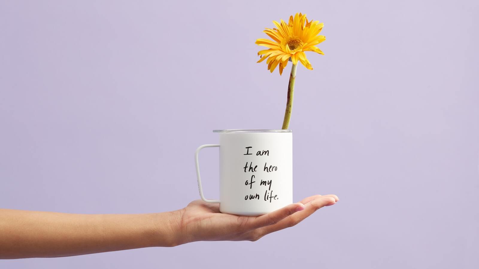 A person holding a mug with a yellow flower in a white mug.
