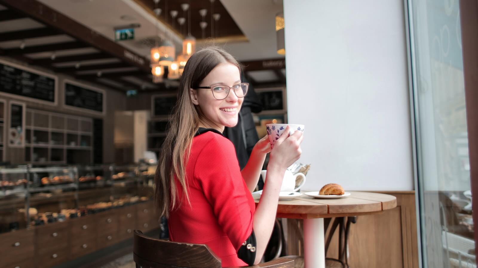 a female student in a red dress drinks tea in a coffee shop