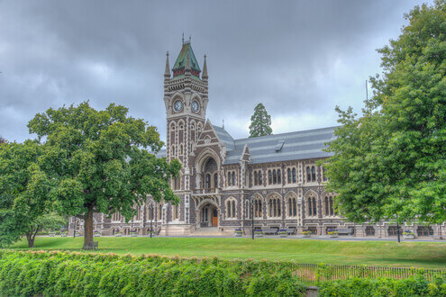 a stunning college building with green grass and a cloudy sky