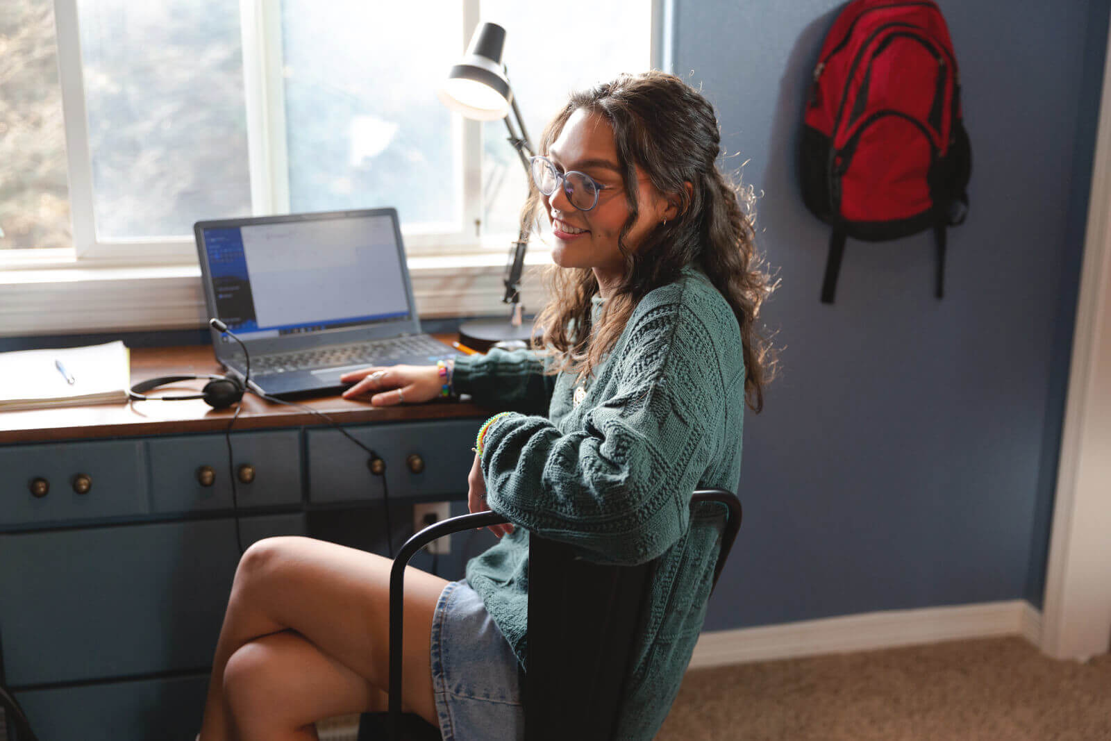 A young lady works at her desk in her bedroom