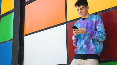 A happy student looking at his phone.