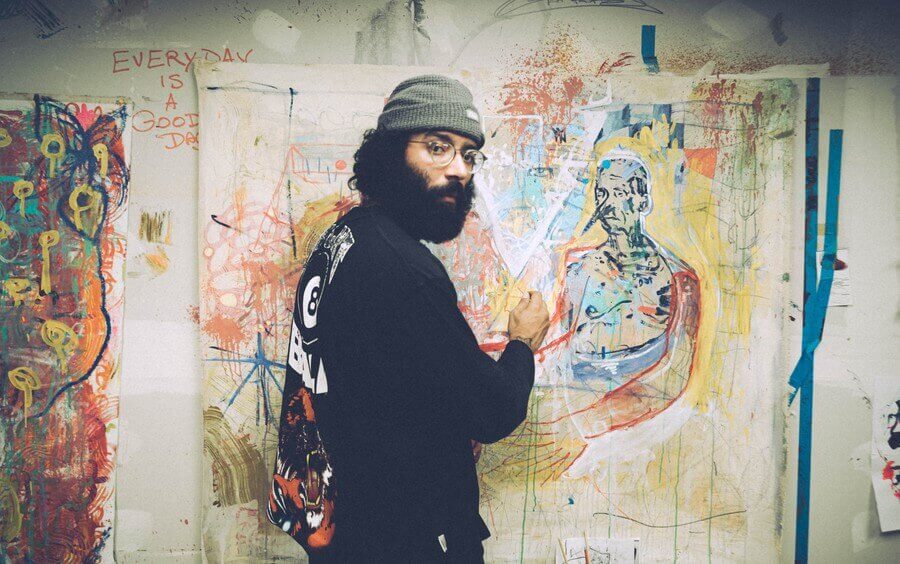 an artist looks at the camera while creating wall art