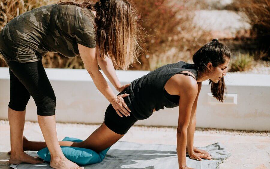 a physical therapist helps a woman with a modified plank