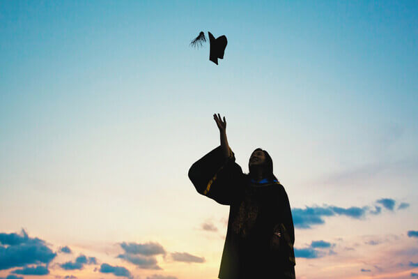 a student throws their graduation cap up in the air