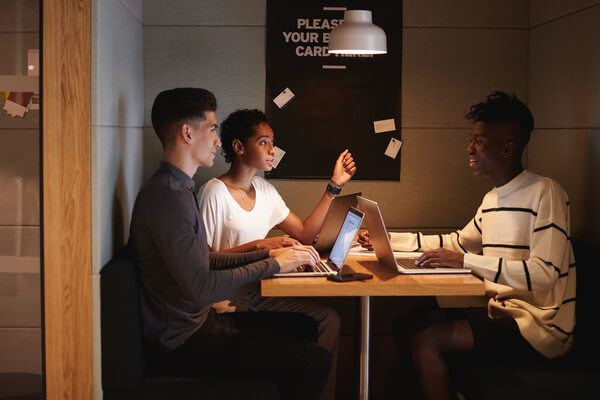three students working as a group on laptops