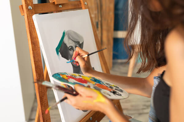 a woman uses oil pain to pain on a canvas