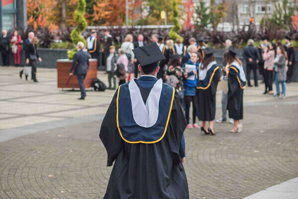 a student wears a cap and gown at graduation