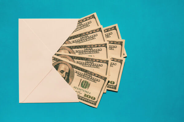 money in an envelope against a teal background