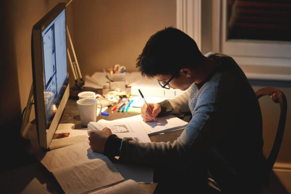 a boy does homework at his desk at home