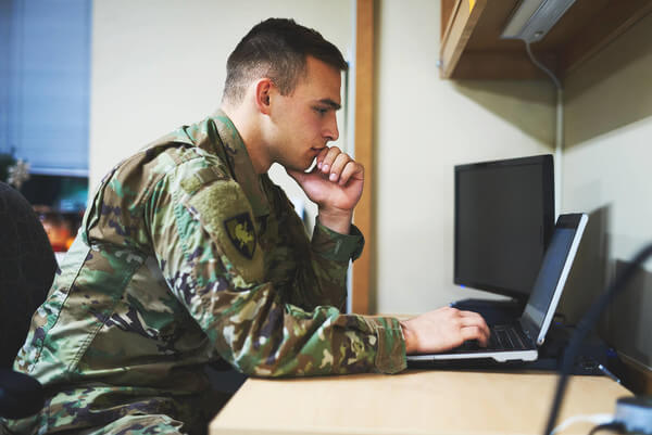 a man in a military uniform looks at his laptop