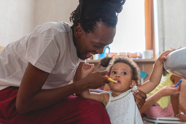 a mother feeds her baby with a plastic spoon