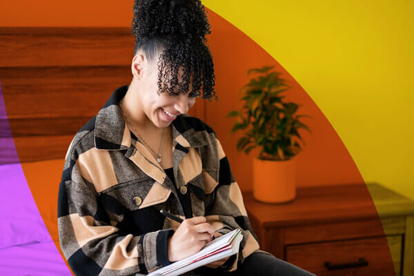 a student writes in a notebook, excited about her senior year of high school