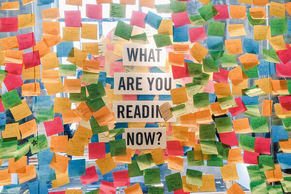 A window covered in post-it notes with the question, "what are you reading now?", in the center.