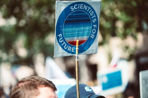 IMAGE: People at a rally with a sign held up overhead saying "Scientist for Future." 