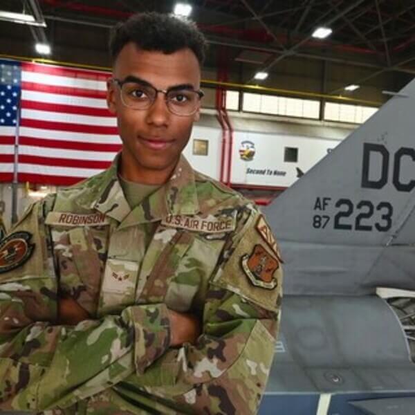 An airman stands in front of an aircraft
