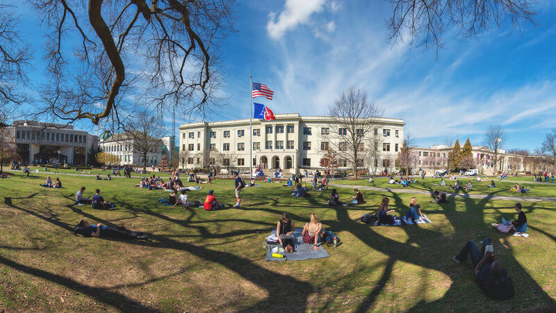 A photo of the campus at American University; students lounging on the green. 