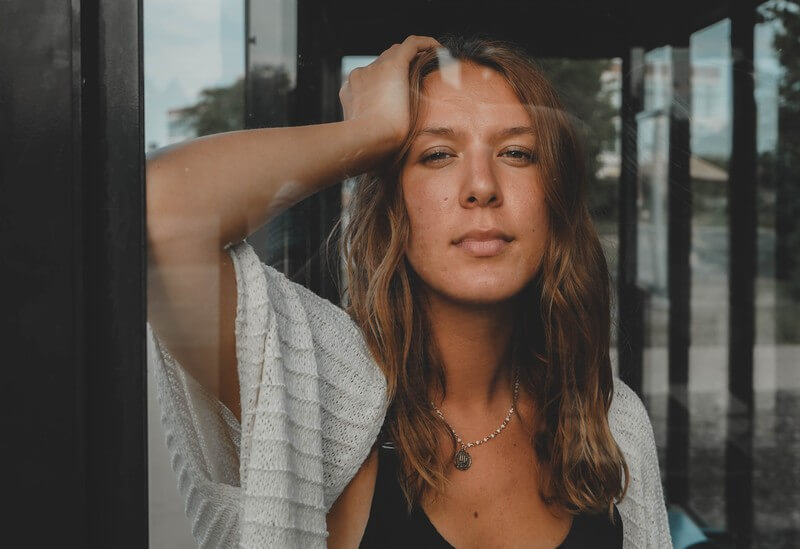 Young woman leaning against a glass wall.