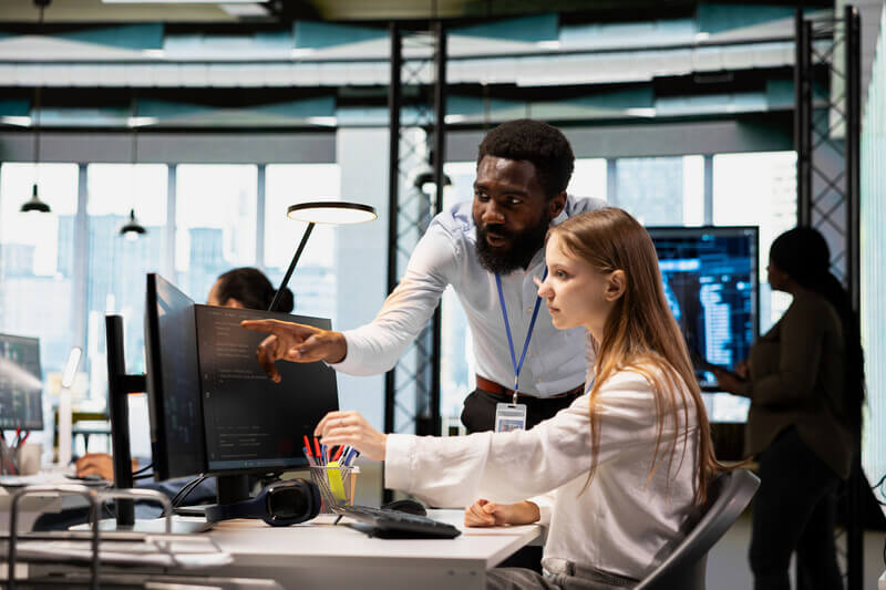 student intern is mentored next to a computer screen