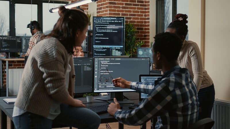 Software engineers gather around a screen