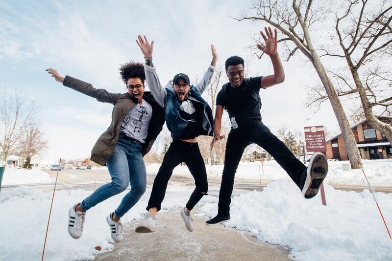 a group of three college students jump with happiness