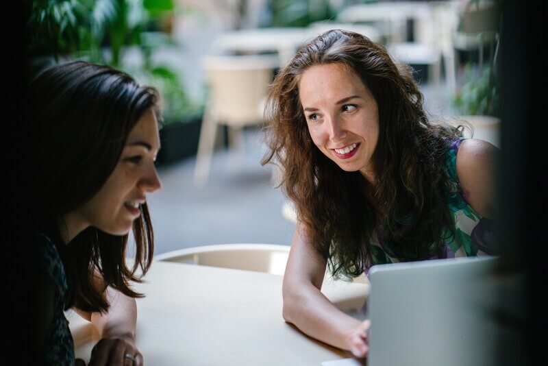 A woman and student smiling and looking at a laptop together.