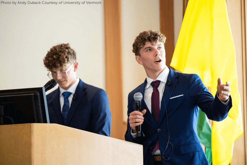 two students stand at the speaker's podium of the University of Vermont