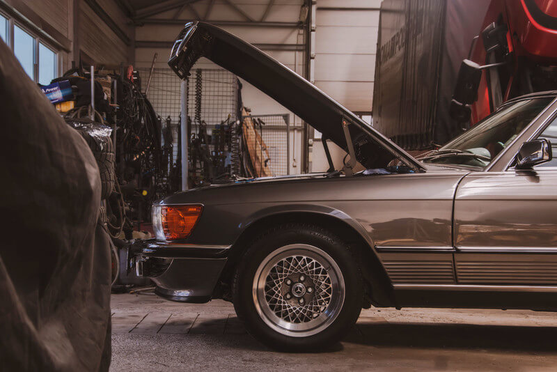 an automotive garage with the hood of a vintage car propped open