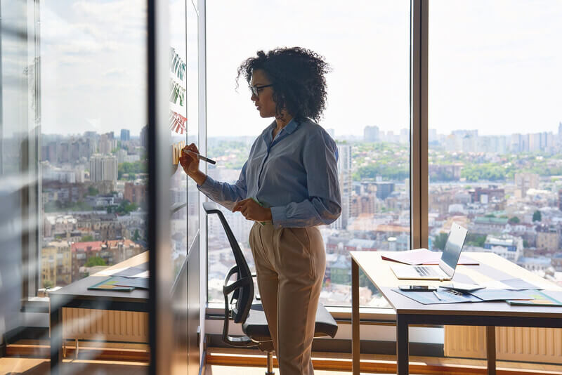 a woman stands at a dry erase board making notes for a meeting