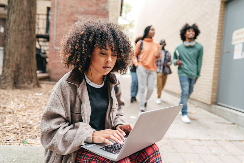 a young woman looks at her laptop to read about the FAFSA