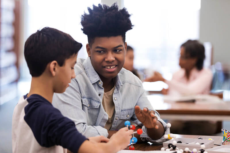 two students talk while building a model in class