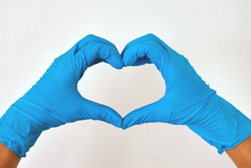 hands wearing medical gloves in the shape of a heart