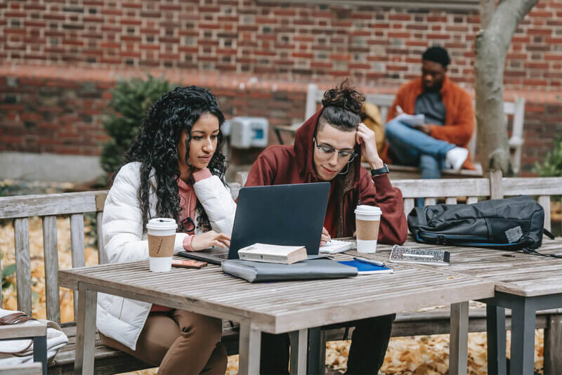 Two students sitting outside at a table
