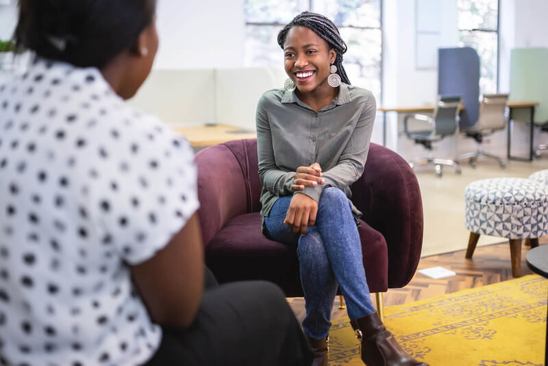 a high school student sits in a chair and smiles during a college interview
