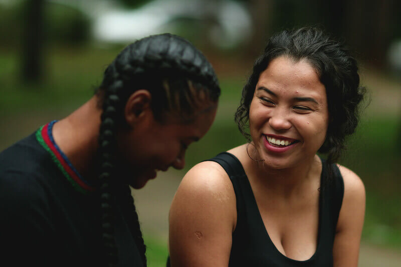 two young women talk and laugh while sitting outside