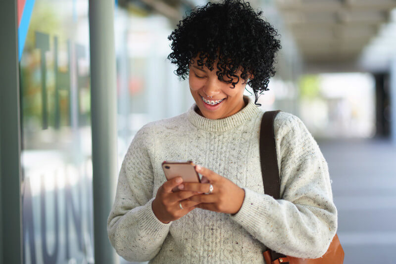 a young lady looks at her phone with a big smile