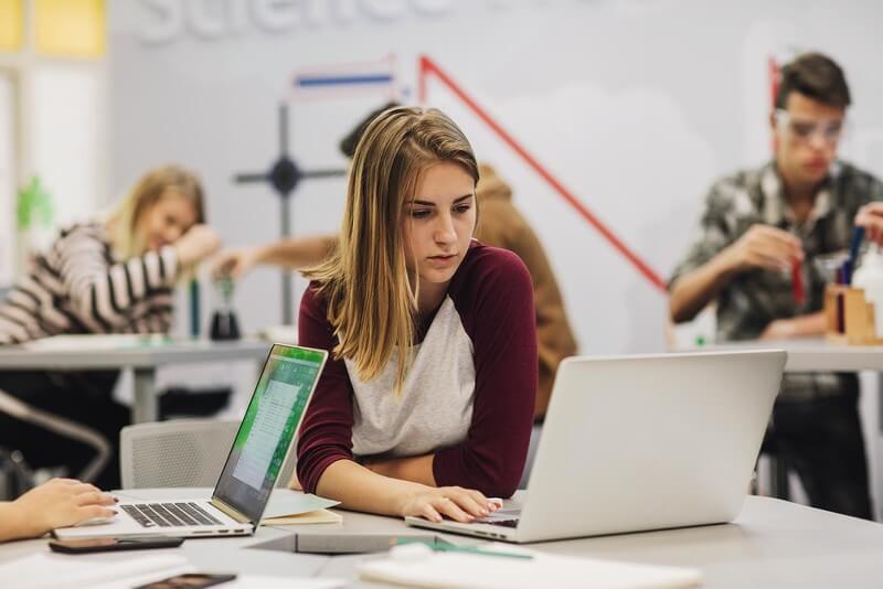 A young woman looking at her laptop as she searches for colleges