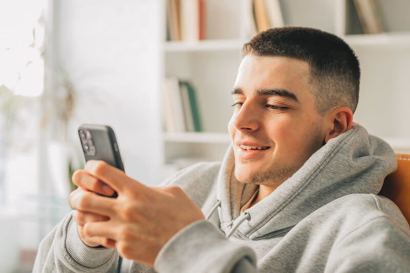 a male teenager looks at a financial aid award letter on his phone