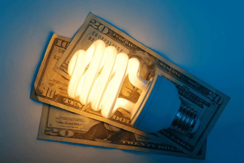 20 dollar bills fanned out with a light bulb on top of them