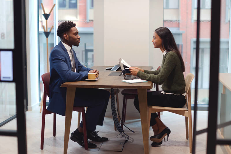 a dressed up man and woman talk at a table